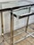Double console table in chromed metal with clear glass tops, dating from the 2000s. Its minimalist, architectural design...