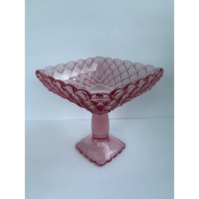 Vintage L.E. Smith pink pressed glass pedestal candy dish or compote in the “Rose & Trellis” pattern. This charming piece...