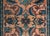 A sweet early 20th century Persian Lilihan rug with a mirrored floral and leaf pattern woven in dark indigo, brick red,...