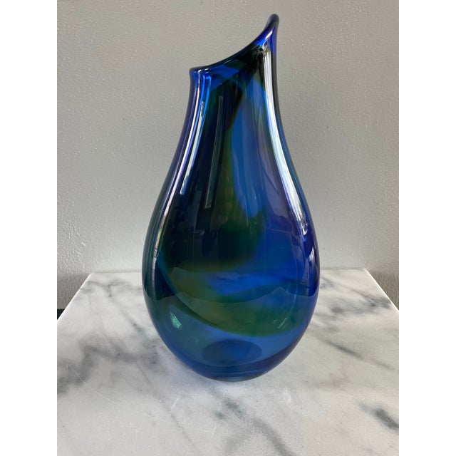 A signed mouth blown art glass vase with a teardrop shape and brilliant blue, green, and purple coloring. Etched Kingwell...