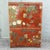 A striking vintage Chinese armoire featuring a rich red lacquer-style finish with elaborate hand-painted botanical and...