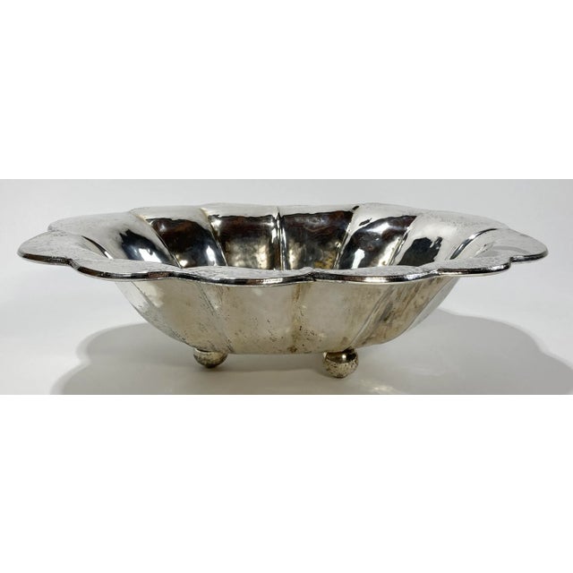 Large vintage hammered silverplate bowl with scalloped edge. Three exaggerated ball feet raise bowl. Patina to silver....