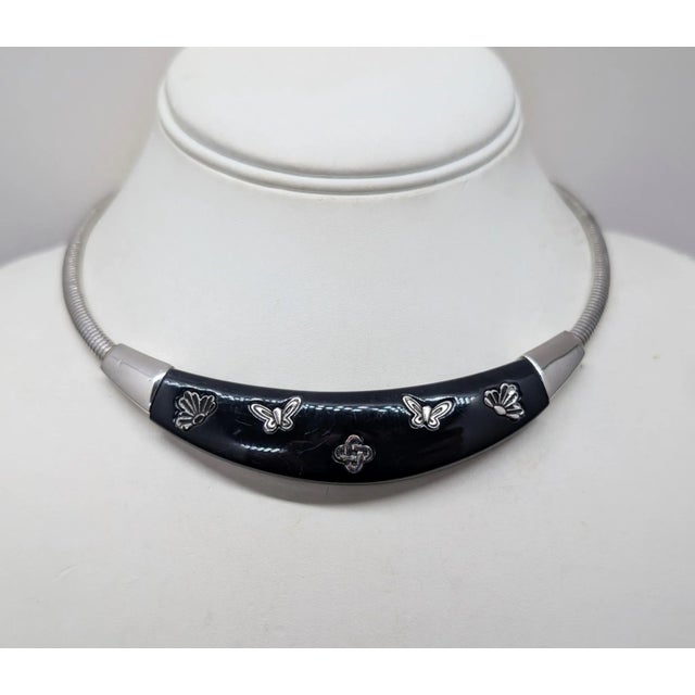 Rhodium plated navy blue resin with butterflies, lotus flowers and knot collar necklace with fold over clasp. Marked "©...