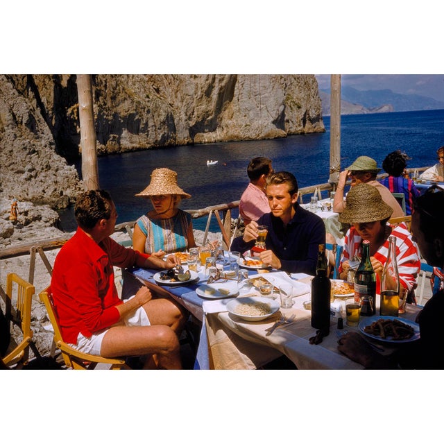 Dining On Capri by Toni Frissell A group of people eating lunch al fresco on Capri. Italy, June 1951. (Photo by Toni...