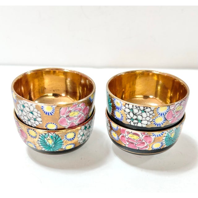 A refined set of four Japanese porcelain bowls, hand-decorated with vibrant floral motifs and accented by richly gilded...
