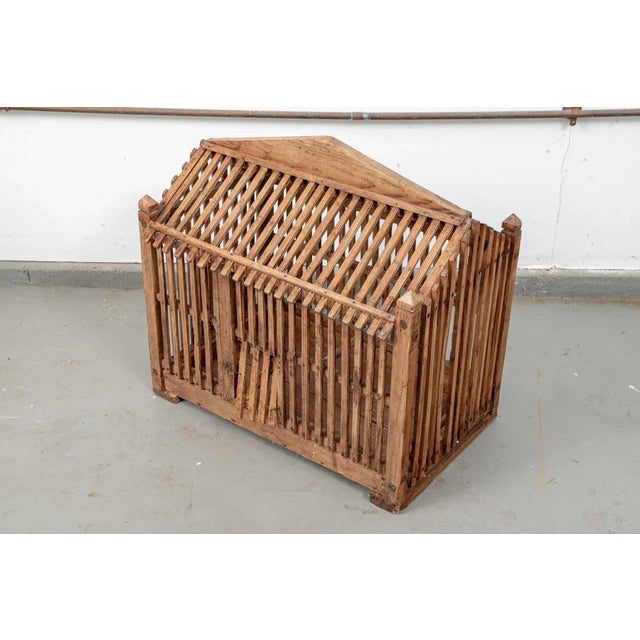 An antique wooden rectangular birdcage constructed of thinly hand carved wooden slats with a peaked A-framed roof, corner...