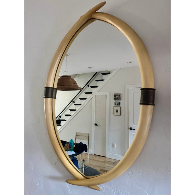 Unusual 1970's faux tusk mirror with patinated brass accents manufactured by Chapman in 1976. Made of a composite...