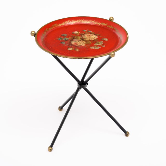 Tea table from France made of lacquered metal. The piece has a lovely red hue and gold leaf detailing throughout. The top...