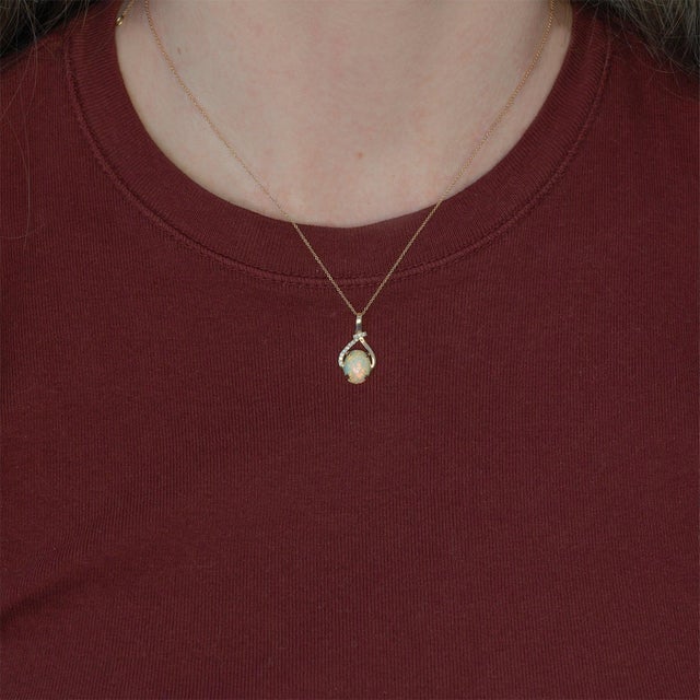 Elevate your jewelry collection with this stunning Ethiopian Opal pendant necklace. The mesmerizing 10x8mm oval opal...