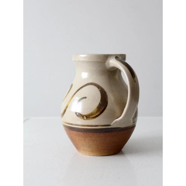 This is a vintage studio pottery pitcher dated 1996. Signed by the artist, the handmade ewer has a natural toned glaze...