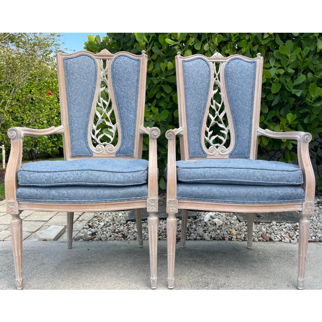 Elegant pair of French Provincial style armchairs featuring tall shaped backs with intricate open foliate carvings, fluted...