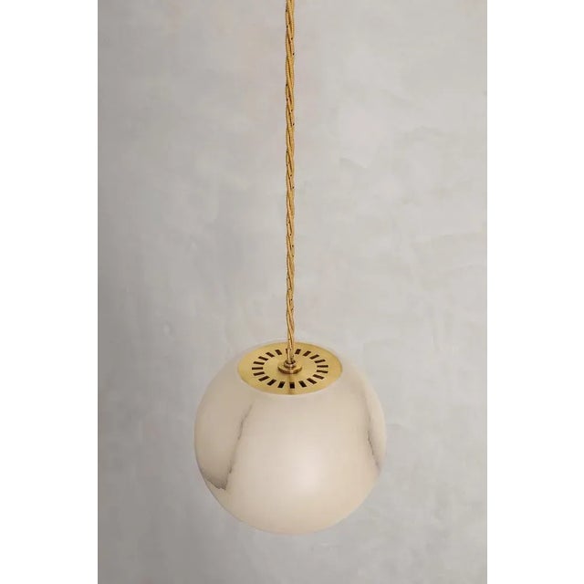 Planette cable 12 pendant by contain dimensions: ø 12 x h 100 cm (custom lenght). Materials: alabaster, brass, optical...