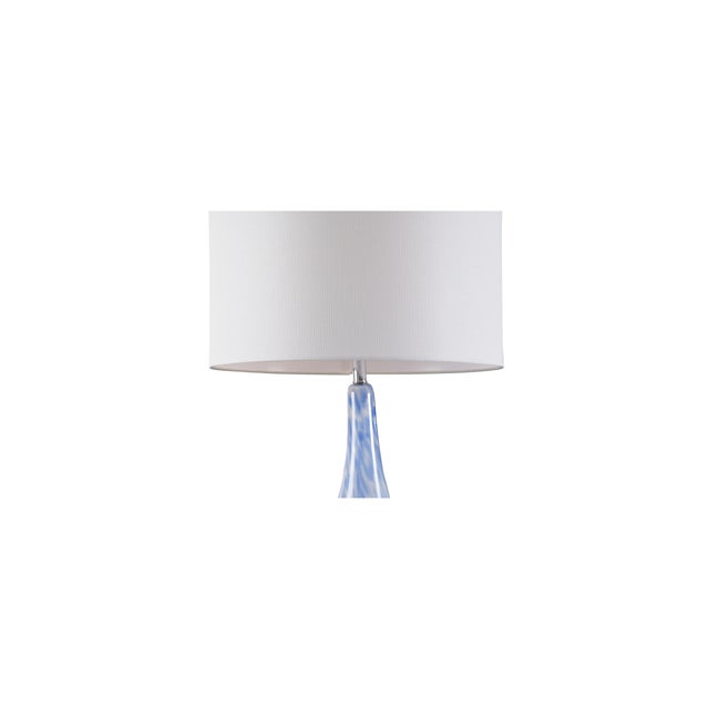 A simple shape gives a clean and airy look to the elio lamp. Its opaque white and light blue glass sits atop an acrylic...