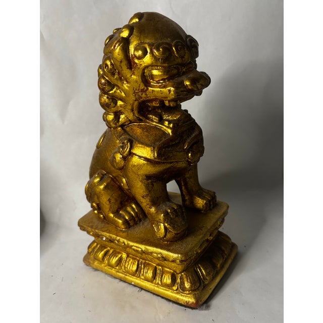 A richly modeled Chinese Buddhist guardian lion, or shishi, seated on a tiered lotus-form pedestal and finished in warm...