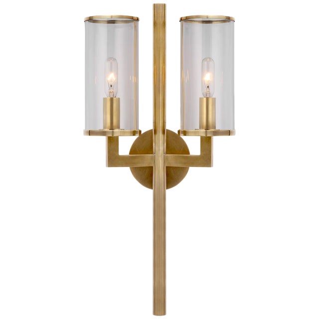 Liaison Double Sconce in Antique-Burnished Brass with Clear Glass Designer: Kelly Wearstler Height: 19" Extension: 5.25"...