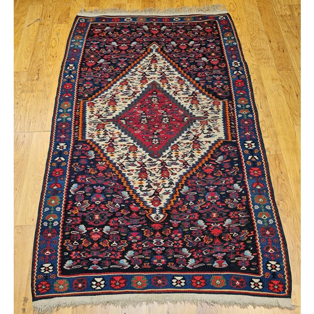 A masterful example of Persian textile artistry, this mid-20th century Senneh kilim area rug showcases the refined weaving...