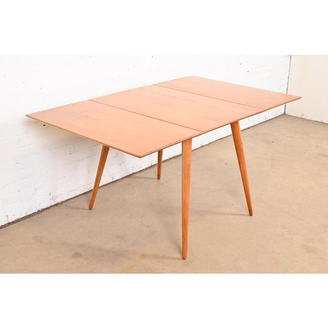 A sleek and stylish Mid-Century Modern solid maple drop-leaf dining table By Paul McCobb for Winchendon Furniture,...