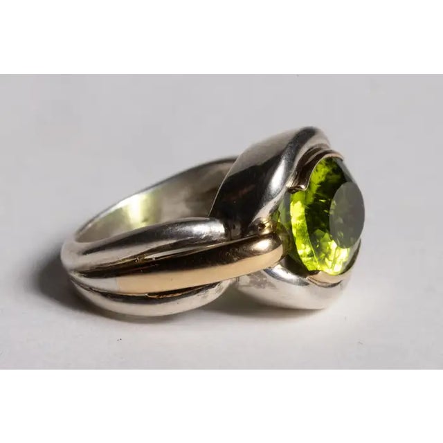 A brilliant 8 carat faceted oval peridot is the star of this stunning ring. The ring itself is a combination of 18K gold...