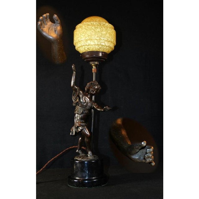A highly decorative and substantial art deco figural table lamp dating to circa 1920, combining sculptural bronze, black...