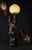 A highly decorative and substantial art deco figural table lamp dating to circa 1920, combining sculptural bronze, black...