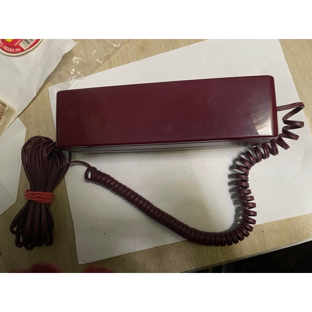 Here is a very mid century telephone that has a streamlined inconspicuous rectangular shape and burgundy color. It would...