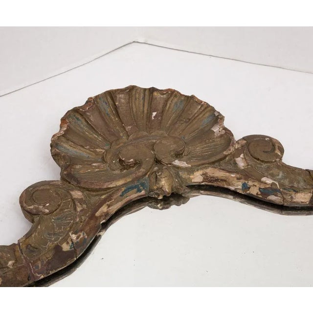Very old gold gilded wood wall mirror with an elaborately carved frame of rosettes, scrolls, and leafs, topped with a...