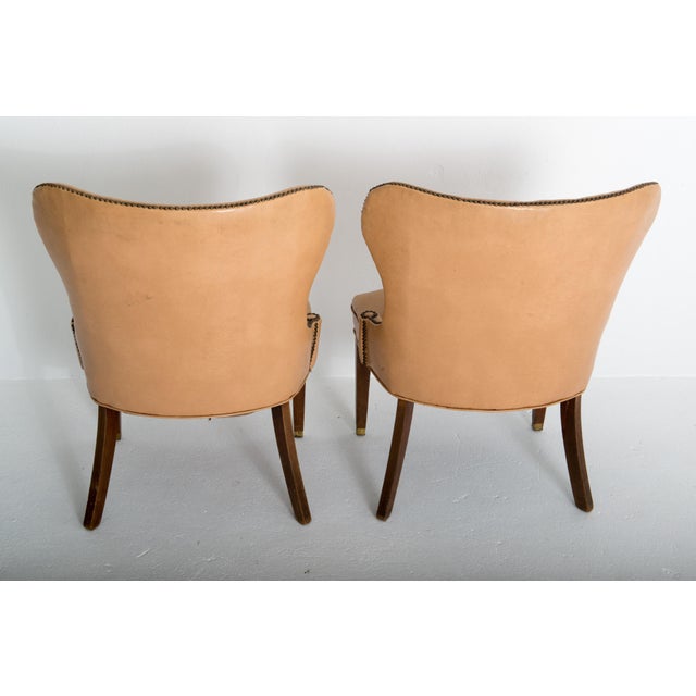 This is a pair of stunning Grosfeld House club chairs in the original beige-camel colored faux leather, nail head studded...