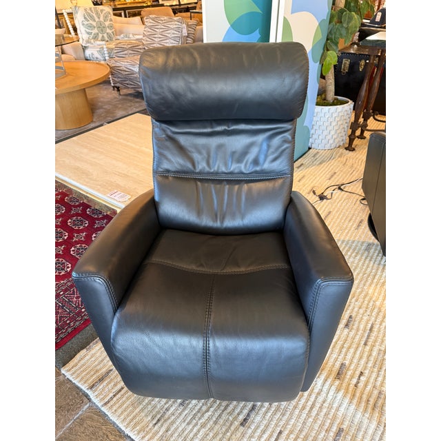Design Plus Gallery presents a Power Swivel Recliner from Fjords. This black leather recliner has padded arms, a channel-...