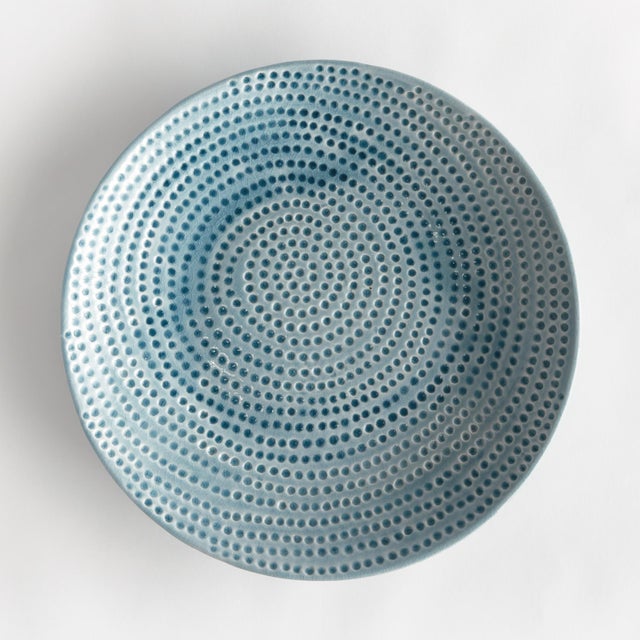 This decorative ceramic plate with a dynamic reactive glaze features a highly textured organic dot pattern that is...