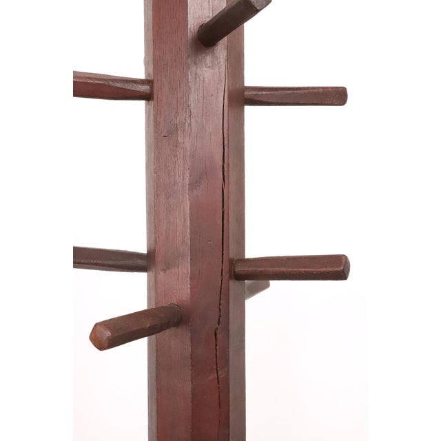 Rustic style coat rack made of dark stained walnut with a simple design. It features a square column central post, eight...