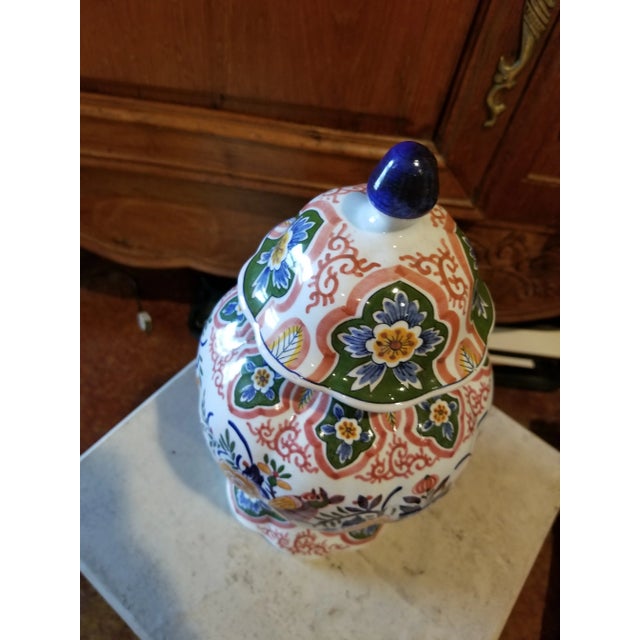 Pretty vintage multi colored storage jar with lid with blue marks on the bottom.