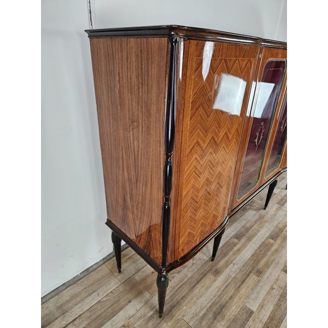 An elegant 1960s Italian display cabinet, veneered in walnut and featuring light, refined lines reminiscent of Mid-Century...