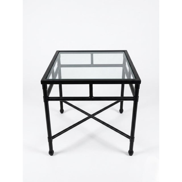This elegant side table features a robust yet refined hand-forged iron frame finished in a sleek, matte black powder...