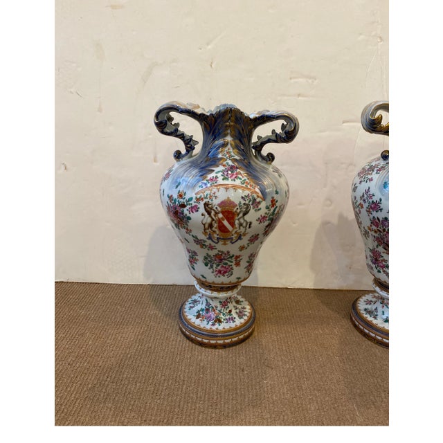A pair of hand painted porcelain with armorial cartouches on the fronts and bouquets of flowers on the backs. The shapely...