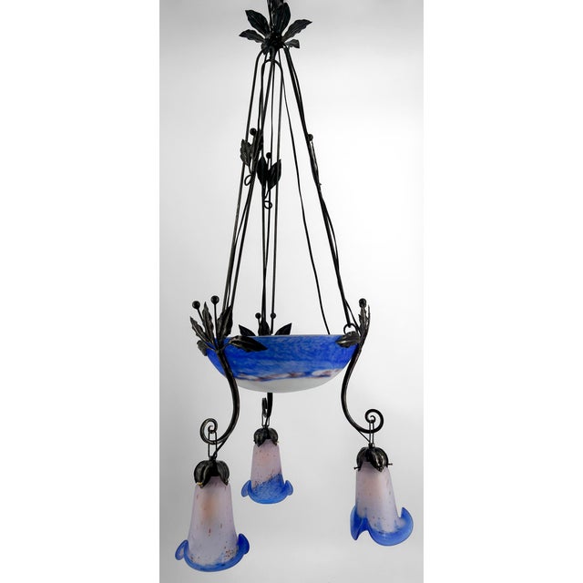 We present to you an exceptional chandelier, a centerpiece of the Art Deco style, perfectly combining forged iron and blue...