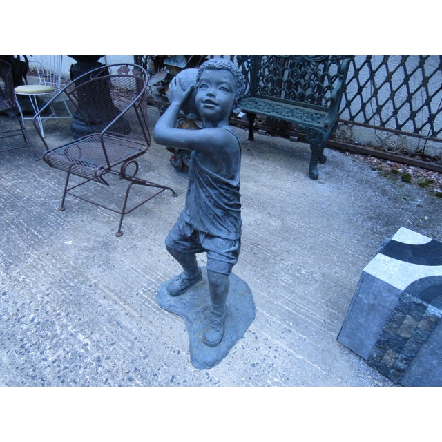 This sculpture of a young boy shooting a basketball is cast in bronze with an aged patina. Condition: Age appropriate...