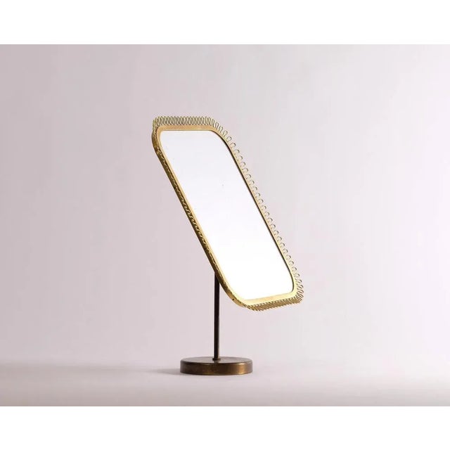Table mirror in brass, possibly manufactured by Nordiska Kompaniet, 1950s. Brass, wave-shaped border decoration. Adjustable.