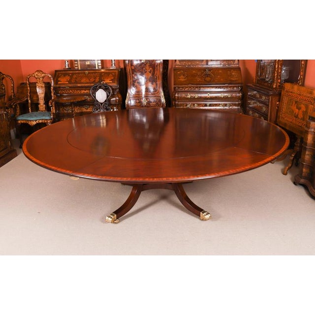 This is a fabulous vintage regency revival flame mahogany jupe circular extending dining table, made by the master cabinet...