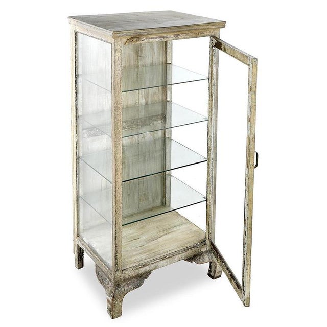 This display case on wooden legs, with a subtle white patina and glass walls, exudes the charm of yesteryear while...