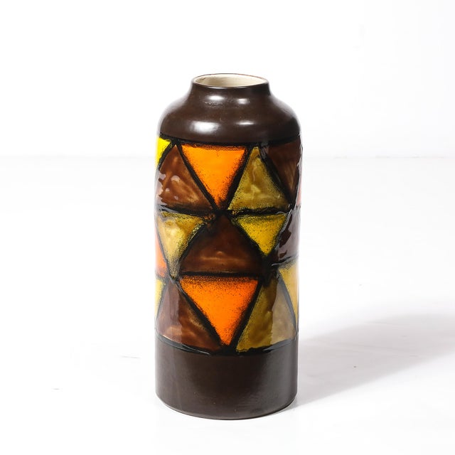 A striking Mid-Century Modernist ceramic vase in burnt umber, featuring bold yellow and orange triangular patterning,...