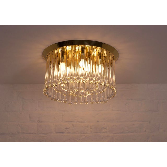 Circular ceiling light made up of a beveled solid brass base supporting 4 rows of crystal drops, original edition from the...