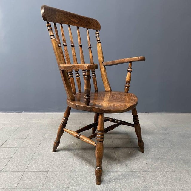 Antique English Windsor chair made of elm wood, around 1900. The high back is equipped with elegant twisted bars and the...