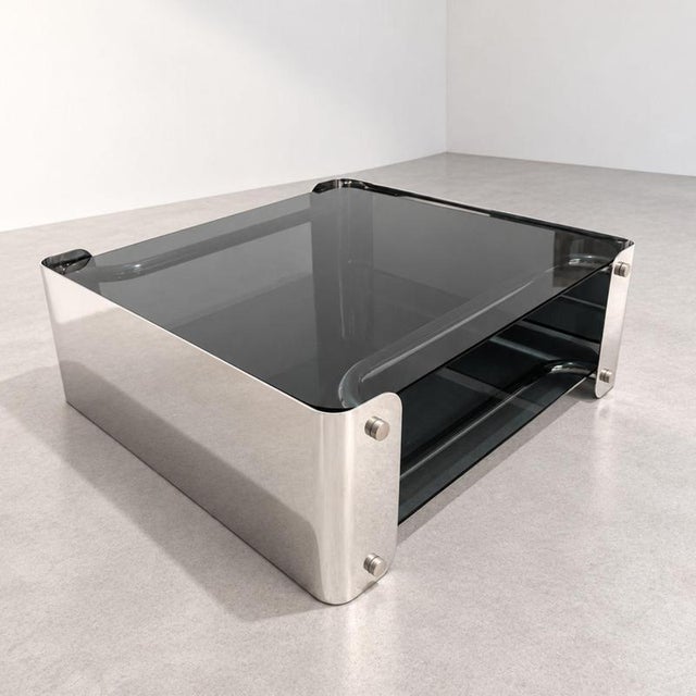 An elegant Italian coffee table from the 1970s, crafted from smoked glass and chrome-plated metal, featuring a refined...