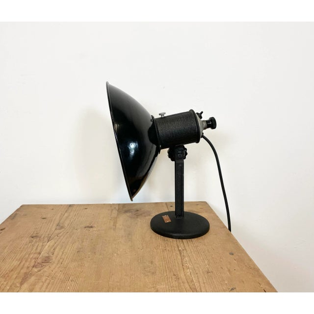 Industrial adjustable table lamp from former Czechoslovakia made during the 1950s. It features a black enamel shade with...