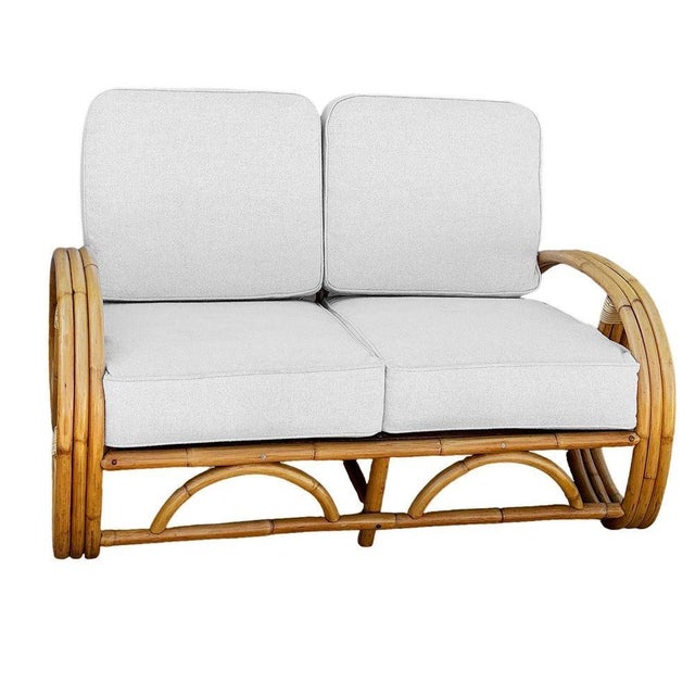 This beautifully restored Post War three strand, 3/4 round pretzel arm rattan section loveseat sofa for2 people, features...