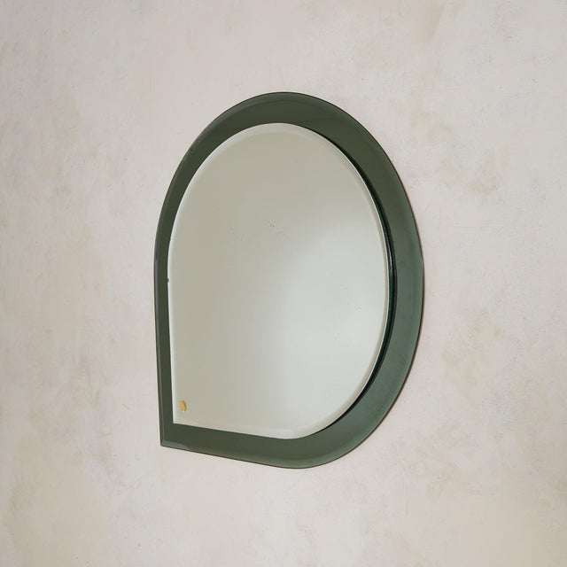 A 1950s Italian wall mirror in thick green glass, crafted in the manner of Fontana Arte. Its teardrop form feels...