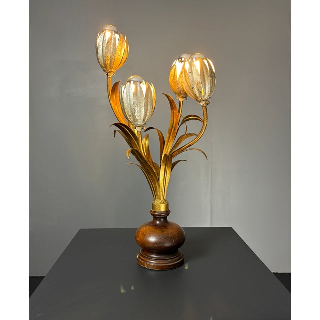 A four-light table lamp in gilt tole, formed as a spray of tulip-form buds rising from sword-leaf foliage, mounted on a...