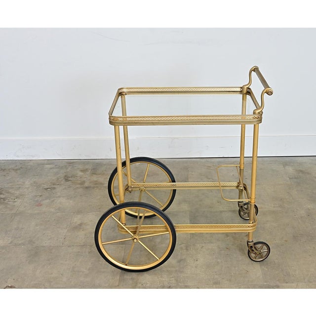 An elegant, mid-century French brass and transparent glass bar cart in the style of Maison Jansen, that would be...