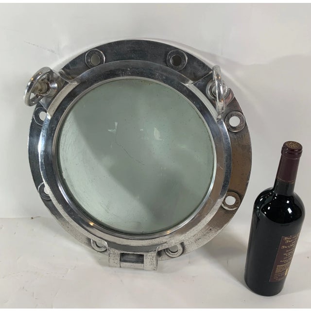 Authentic polished aluminum ship's porthole fitted with a glass window. Door is hinged and fitted with two dogbolts....