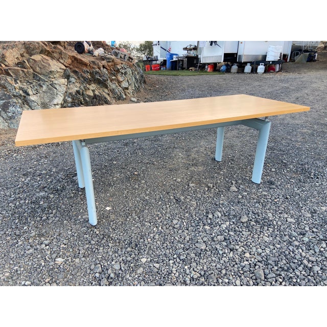 The Cassina Le Corbusier LC6 dining table features a sleek and modern design with a grey metal base and an oak tabletop....